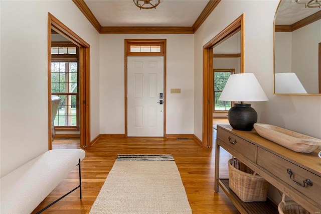 entrance foyer featuring ornamental molding, light wood-type flooring, and a wealth of natural light