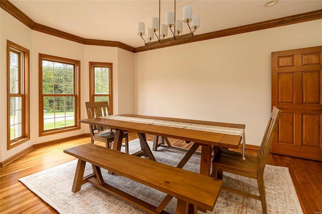 dining space with hardwood / wood-style flooring, ornamental molding, and a chandelier