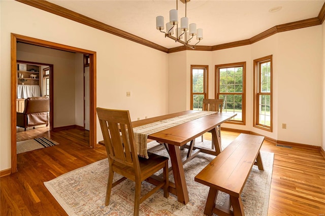 dining room with crown molding, hardwood / wood-style flooring, and a chandelier