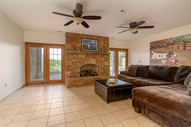 tiled living room with a stone fireplace, french doors, and ceiling fan