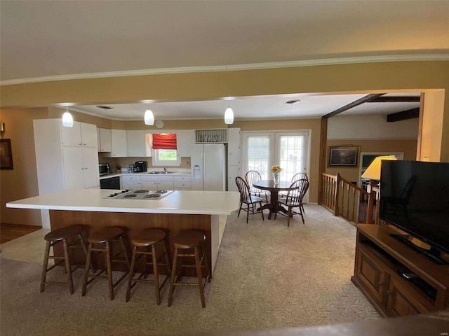 kitchen with a kitchen breakfast bar, light carpet, sink, white cabinetry, and white appliances