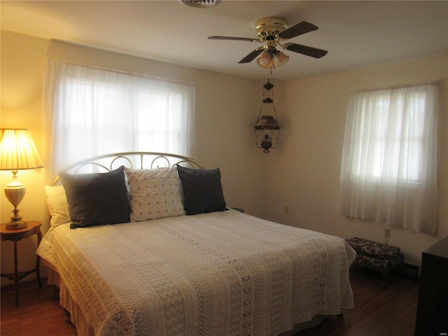 bedroom with ceiling fan, multiple windows, and dark hardwood / wood-style flooring