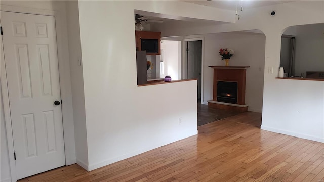 interior space with arched walkways, baseboards, and light wood-style floors