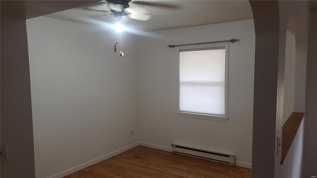 spare room featuring baseboards, a baseboard radiator, ceiling fan, and wood finished floors