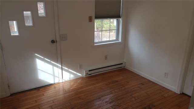 empty room featuring baseboards, a baseboard radiator, and wood-type flooring