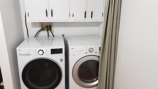 clothes washing area with washing machine and dryer and cabinets