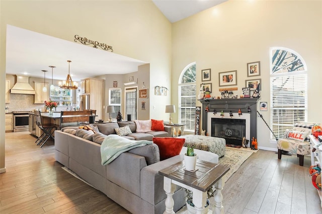 living room featuring a towering ceiling, a notable chandelier, and light wood-type flooring