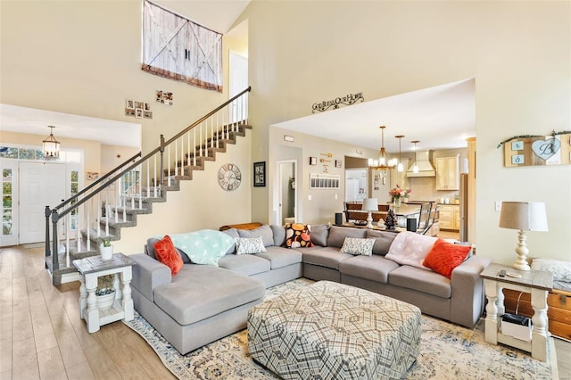 living room with a towering ceiling, light hardwood / wood-style flooring, and an inviting chandelier