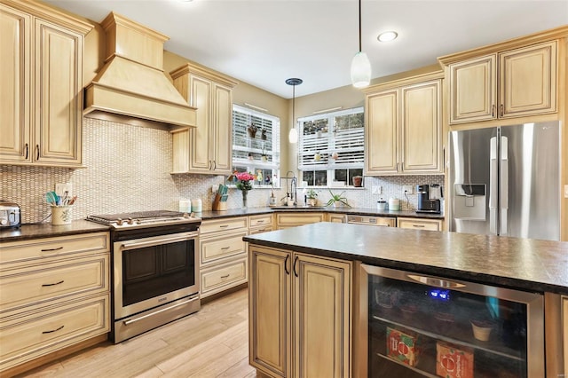 kitchen with beverage cooler, appliances with stainless steel finishes, premium range hood, pendant lighting, and light hardwood / wood-style floors