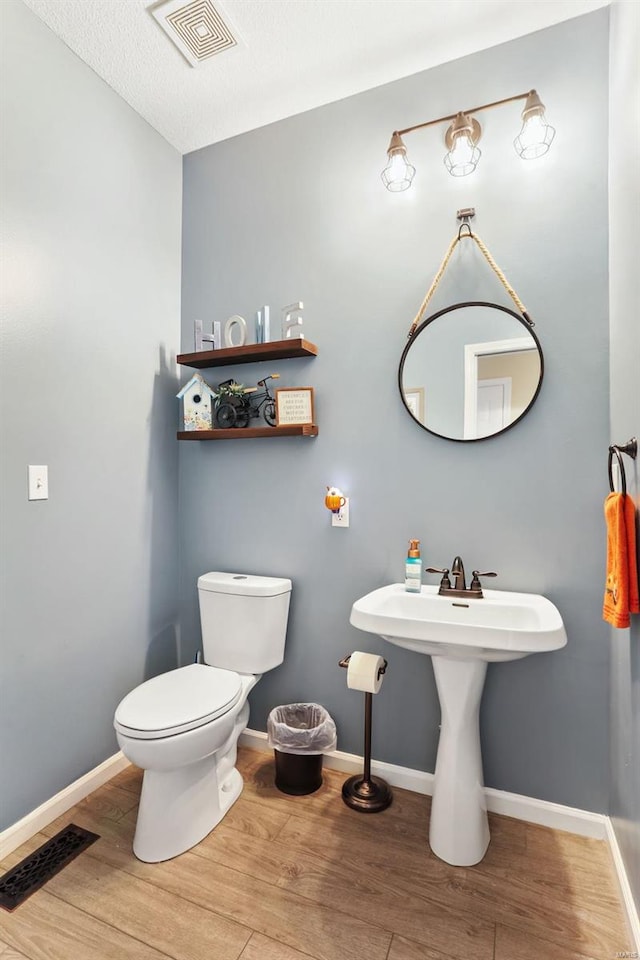 bathroom featuring wood-type flooring and toilet