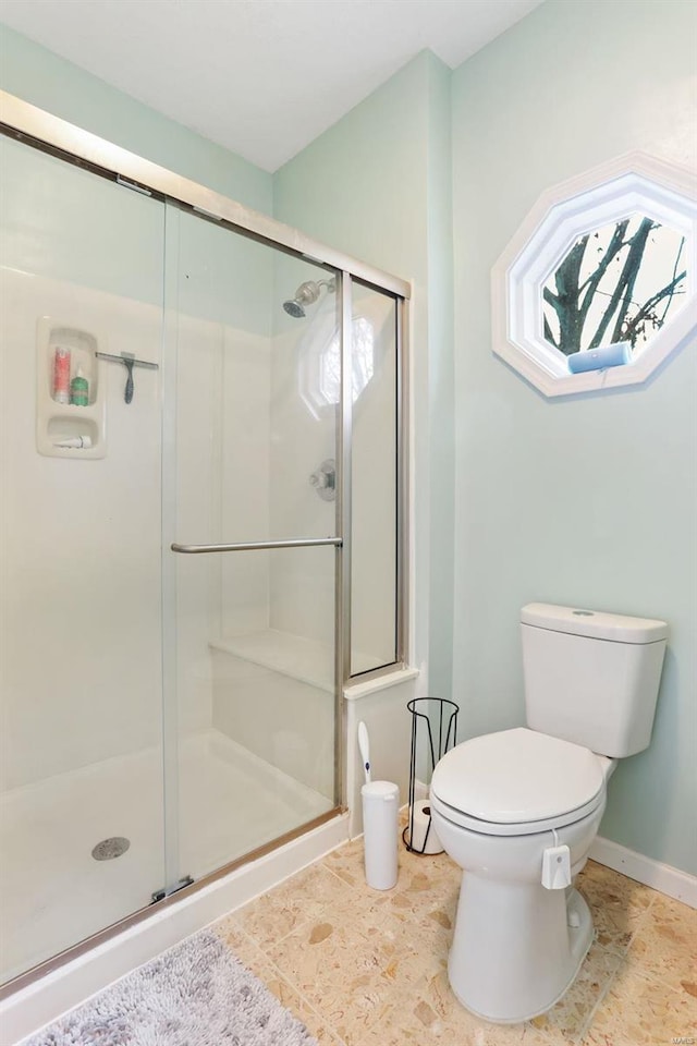 bathroom with a shower with door and toilet