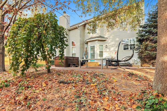 rear view of property featuring a hot tub and a patio area