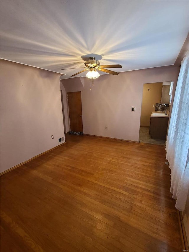 empty room featuring ceiling fan, light wood-type flooring, and sink