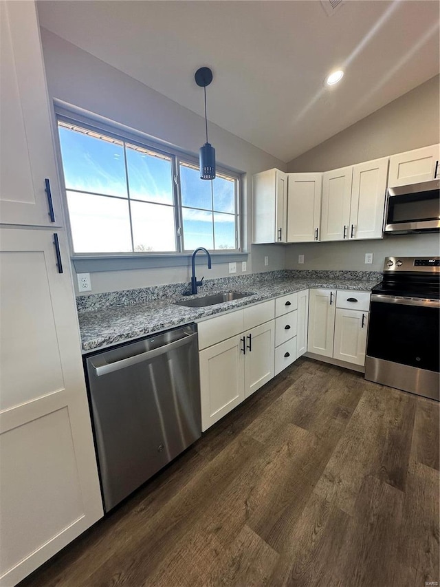 kitchen featuring a sink, white cabinetry, vaulted ceiling, appliances with stainless steel finishes, and light stone countertops