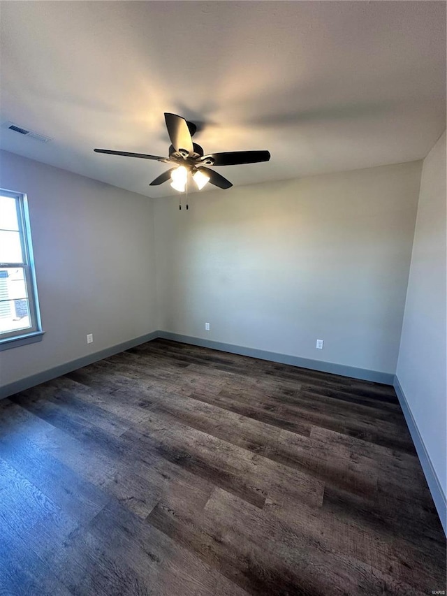 empty room featuring a ceiling fan, baseboards, visible vents, and dark wood-type flooring