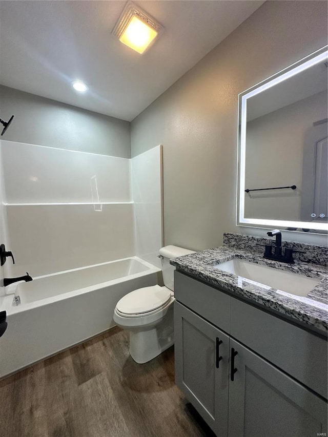 bathroom featuring  shower combination, vanity, toilet, and wood finished floors