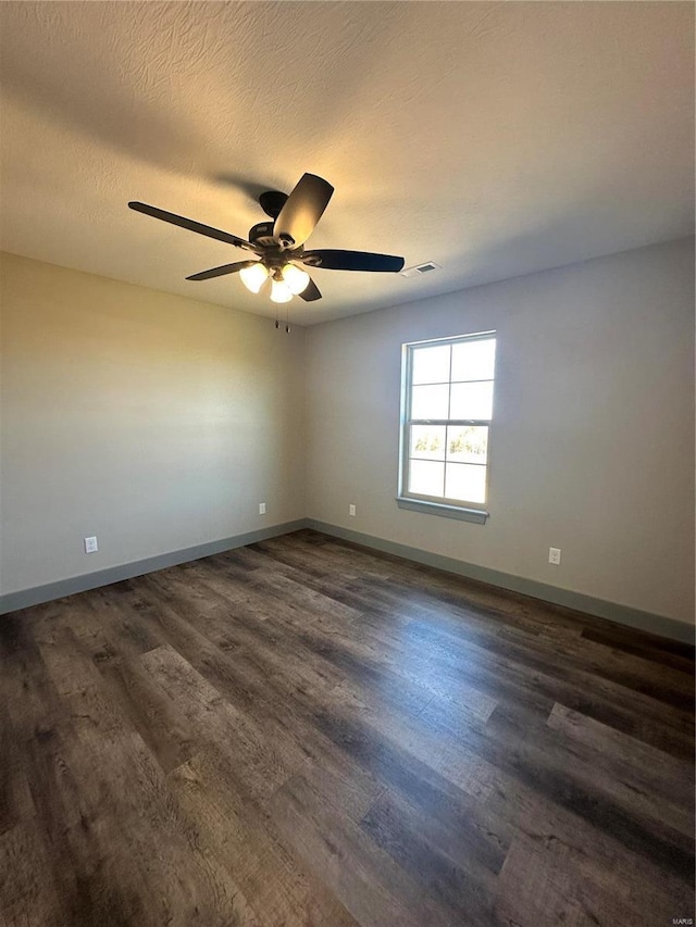 empty room featuring dark wood-style floors, ceiling fan, a textured ceiling, and baseboards