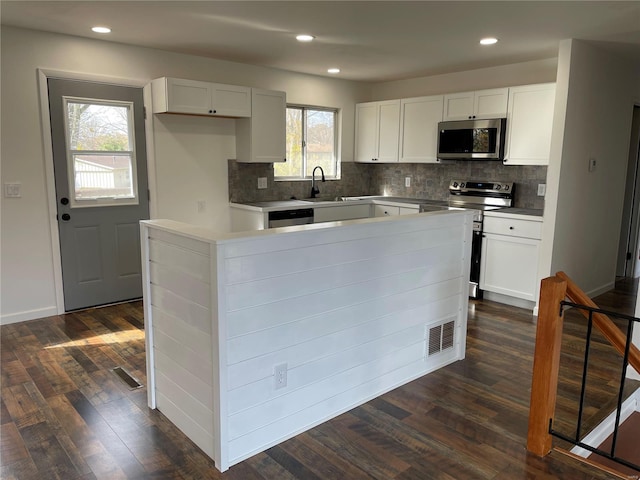 kitchen featuring white cabinetry, stainless steel appliances, tasteful backsplash, dark hardwood / wood-style flooring, and a kitchen island