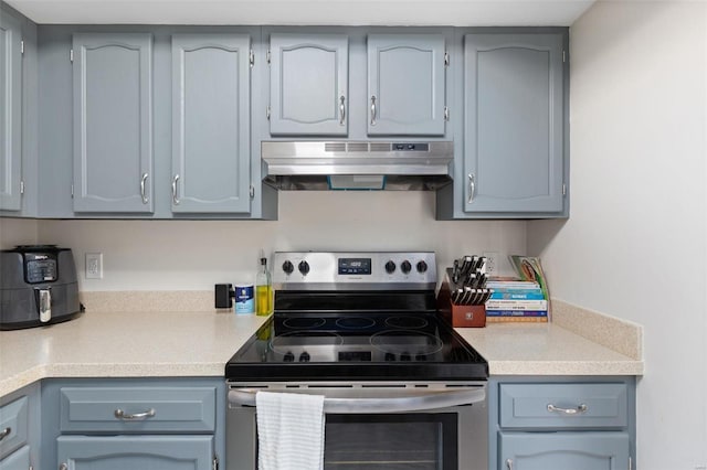 kitchen with stainless steel range with electric stovetop, ventilation hood, and gray cabinetry