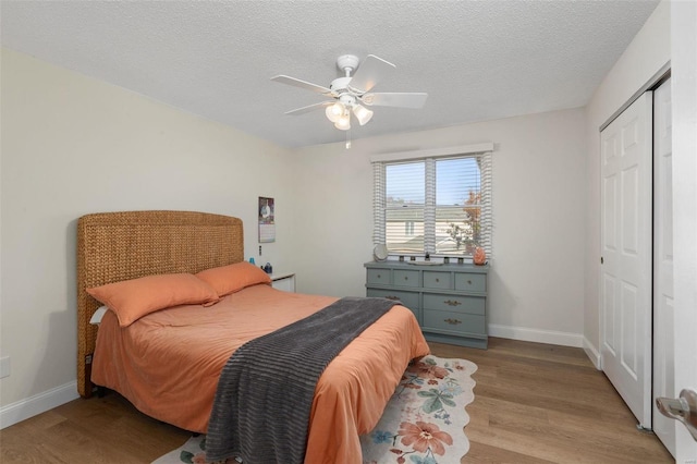 bedroom with light hardwood / wood-style flooring, a textured ceiling, a closet, and ceiling fan