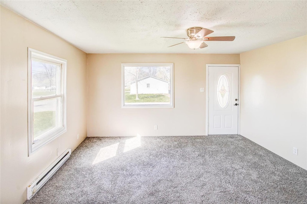 carpeted entrance foyer featuring a textured ceiling, a baseboard radiator, and ceiling fan