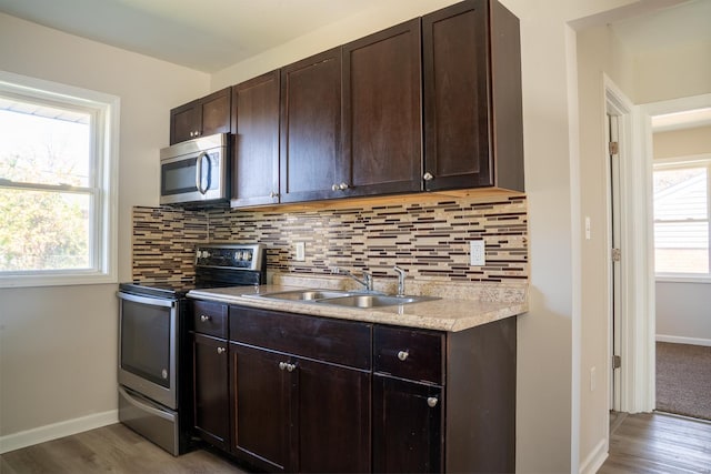 kitchen with dark brown cabinetry, sink, appliances with stainless steel finishes, and light hardwood / wood-style flooring