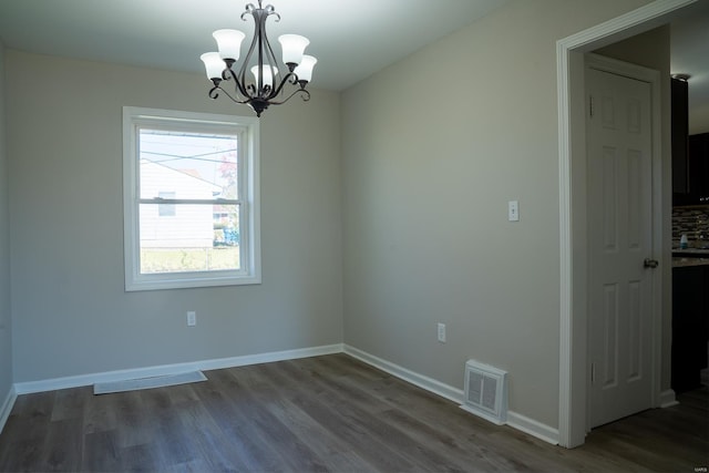 spare room featuring a notable chandelier and dark hardwood / wood-style floors