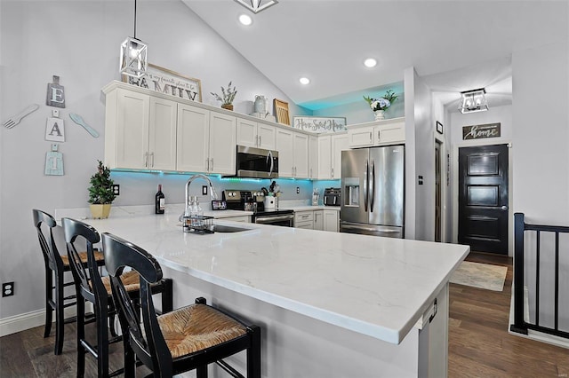 kitchen featuring appliances with stainless steel finishes, sink, kitchen peninsula, decorative light fixtures, and white cabinets