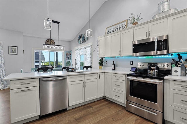 kitchen featuring lofted ceiling, dark hardwood / wood-style floors, stainless steel appliances, pendant lighting, and white cabinetry