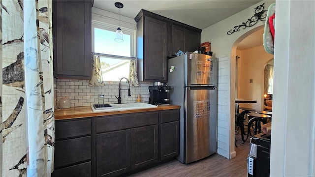 kitchen featuring tasteful backsplash, sink, hardwood / wood-style floors, pendant lighting, and stainless steel refrigerator