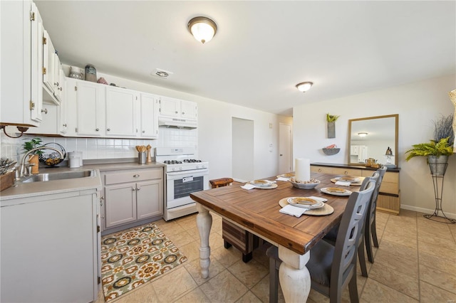 kitchen featuring visible vents, white range with gas cooktop, a sink, under cabinet range hood, and decorative backsplash