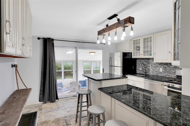 kitchen with a breakfast bar, appliances with stainless steel finishes, dark stone counters, a kitchen island, and decorative backsplash