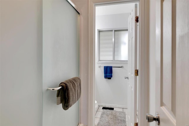 bathroom featuring toilet, tile patterned flooring, and a shower with shower door