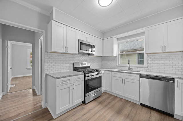 kitchen featuring white cabinets, ornamental molding, sink, light hardwood / wood-style floors, and stainless steel appliances