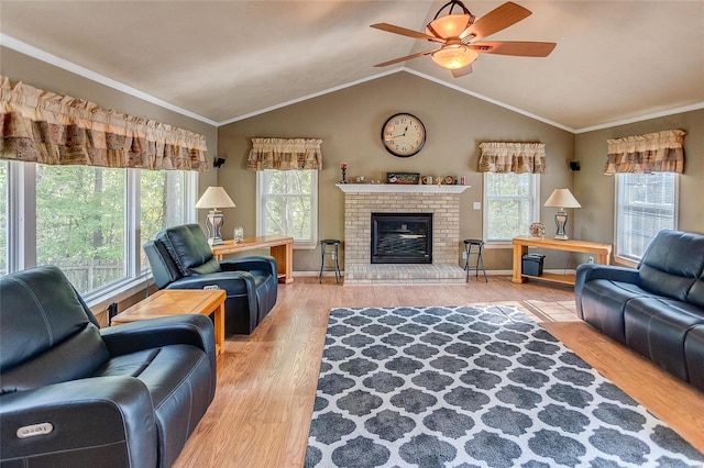 living room with ceiling fan, a fireplace, wood-type flooring, ornamental molding, and vaulted ceiling