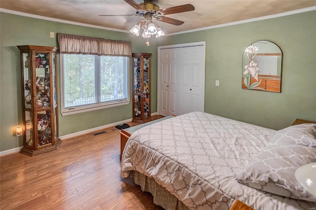 bedroom with ceiling fan, hardwood / wood-style floors, a closet, and ornamental molding