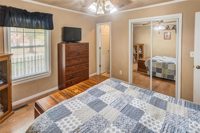 bedroom with ceiling fan, hardwood / wood-style floors, a closet, and crown molding