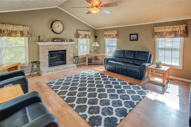 living room featuring wood-type flooring, a fireplace, vaulted ceiling, ceiling fan, and crown molding