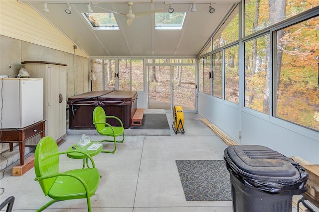 sunroom / solarium featuring vaulted ceiling with skylight and rail lighting