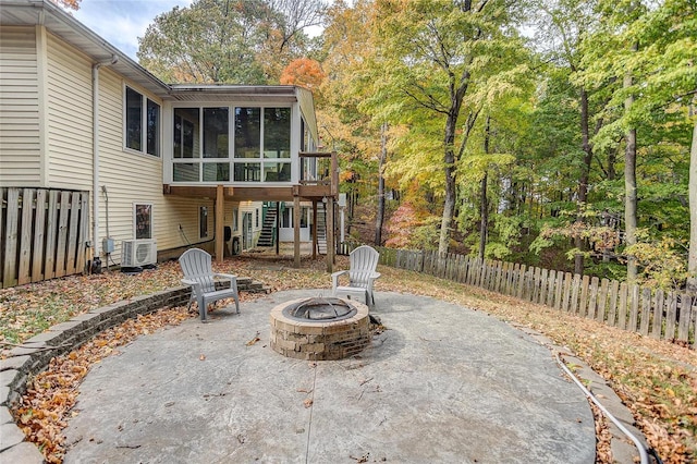 view of patio featuring a fire pit, a sunroom, and cooling unit