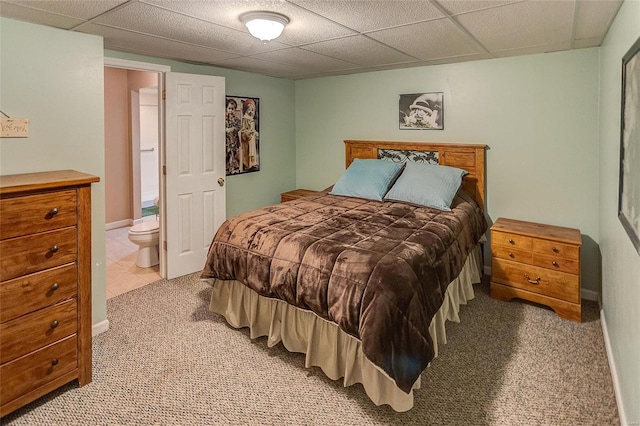 carpeted bedroom with a paneled ceiling and connected bathroom