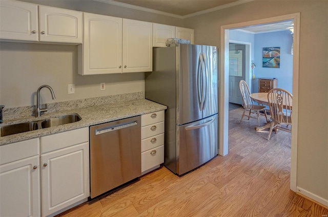 kitchen with crown molding, sink, white cabinetry, light stone countertops, and stainless steel appliances