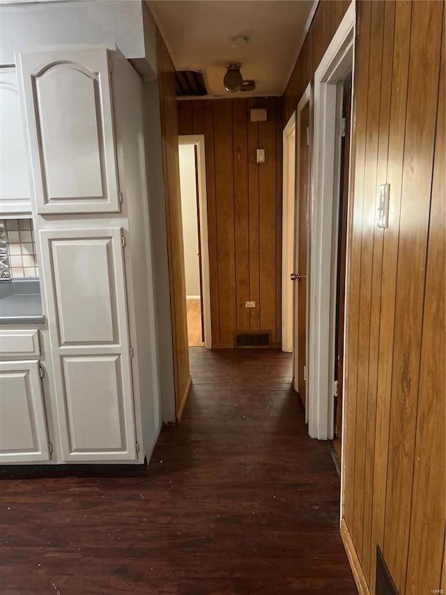 hallway with wood walls and dark hardwood / wood-style flooring