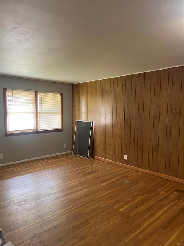 unfurnished room with hardwood / wood-style floors and wooden walls