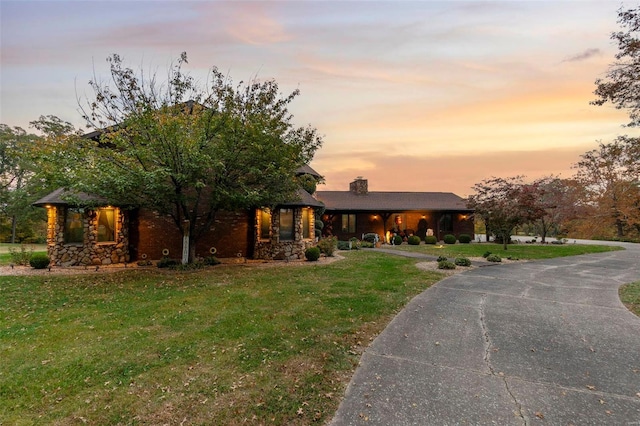 view of front of home featuring a lawn, a chimney, covered porch, and curved driveway