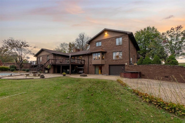 back of house at dusk featuring a yard, a garage, a wooden deck, concrete driveway, and stairs