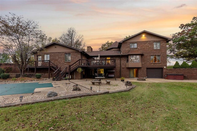 back house at dusk featuring a patio, a wooden deck, a yard, and a garage