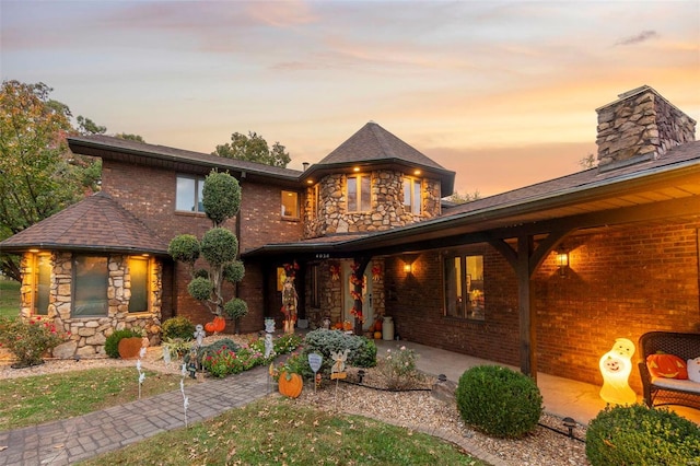 view of front of property with a chimney, stone siding, and brick siding