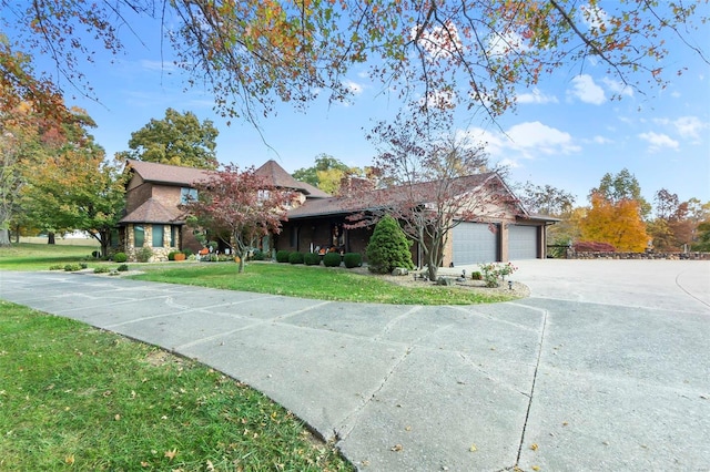 view of front of property featuring concrete driveway, a front lawn, and a garage