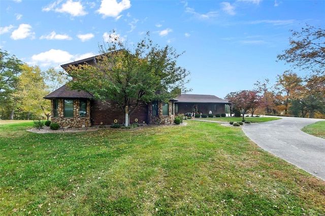 exterior space with a front lawn, driveway, and stone siding